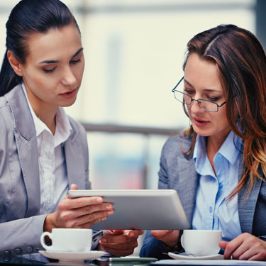 business women viewing webcam footage on tablet computer